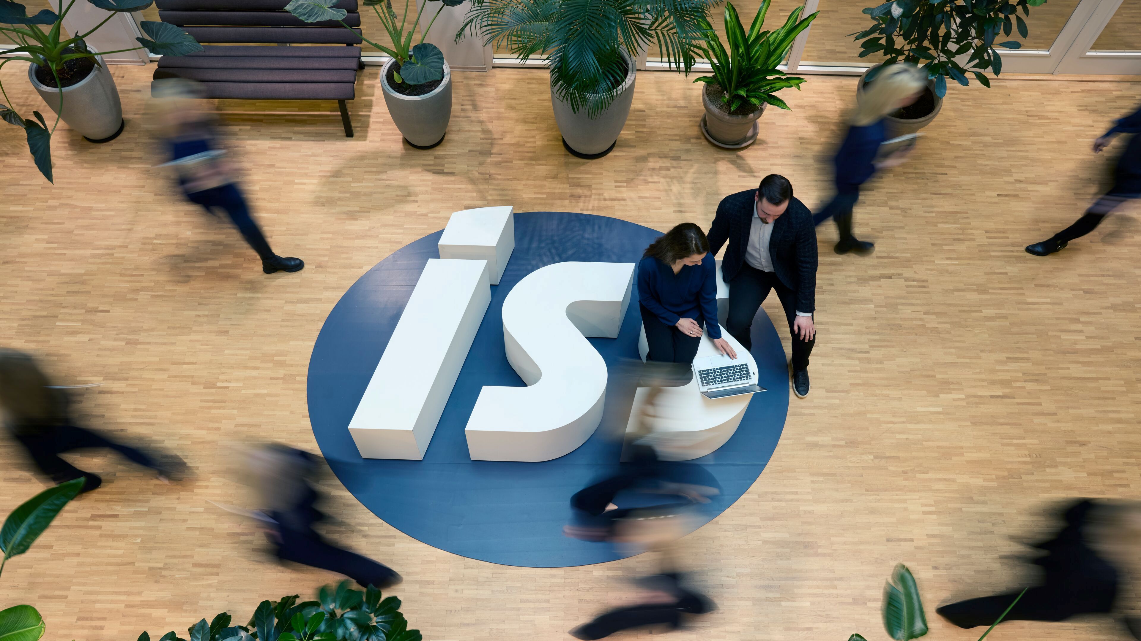 Medarbejdere mødes omkring det store ISS-logo i et lyst kontormiljø.